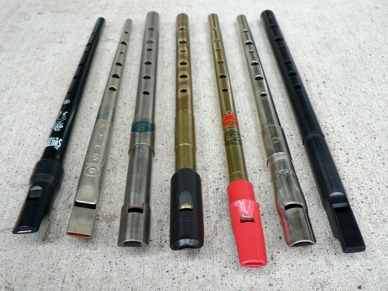 Seven high D tin whistles of different makes and colours laid side by side